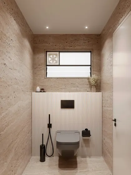 The toilet area in the travertine powder room concept. The design maintains its minimalist and cohesive aesthetic with wall-mounted fixtures and a continuation of the textured wall paneling.