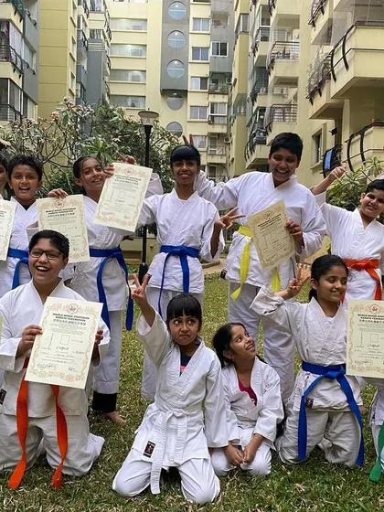 The excitement is visible on every face as students from the Purva Belmont dojo celebrate their new belts and certificates together outdoors.