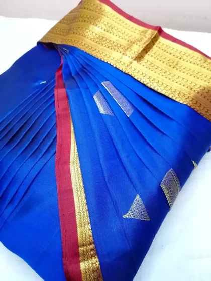 A royal blue saree with a red and gold border. The pleats are done to perfection, making it ready for a quick and elegant drape.