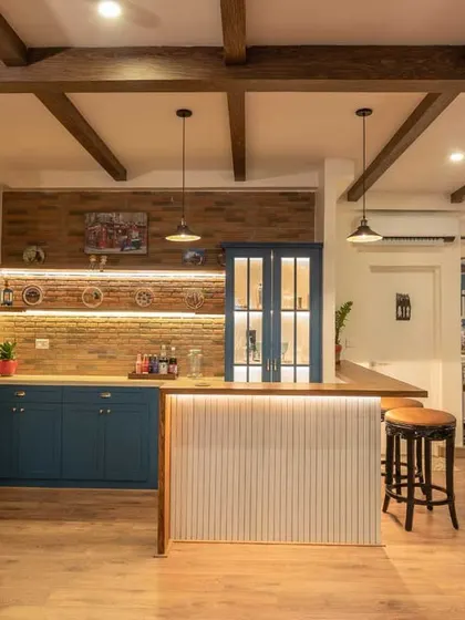 An industrial-style mini-bar with open shelving and closed cabinets in a dusty blue finish, complete with a brick wall backdrop.
