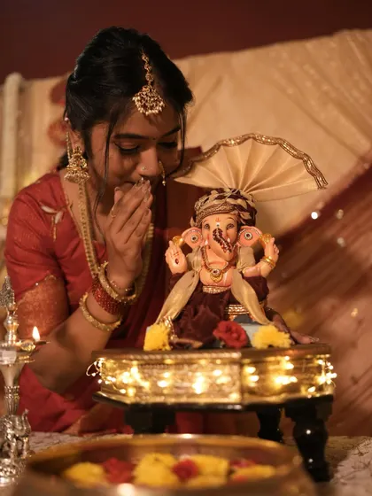 A moment of prayer during Ganesh Chaturthi. The warm lighting and traditional attire create a beautiful, serene mood.