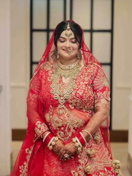 The complete bridal look for Jinal. Her soft glam makeup with beautifully defined eyes and a neutral lip perfectly balances her magnificent red and gold wedding lehenga.