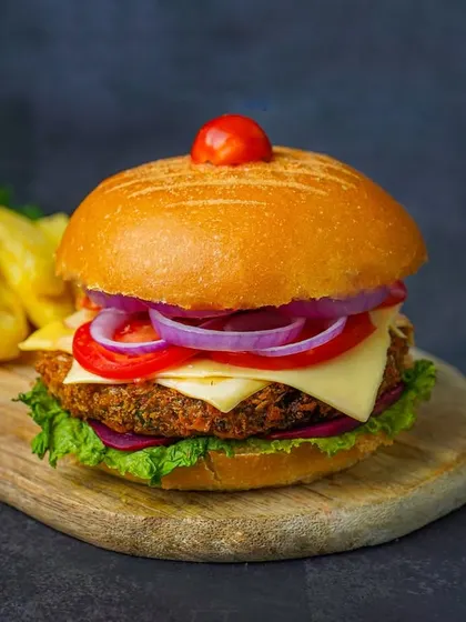A classic veggie burger and fries, styled on a wooden board to create a rustic and appetizing pub-food look.
