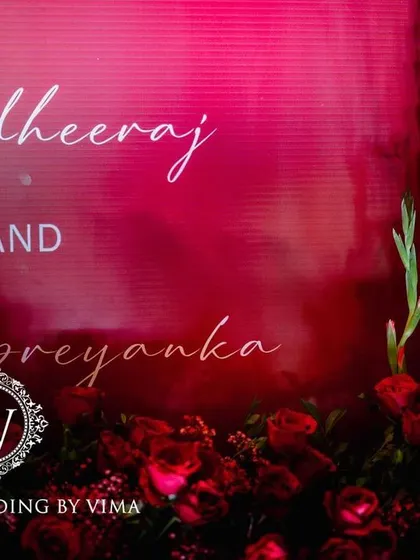 A bold and luxurious reception with a red and black color scheme. The decor includes rich red roses, modern crystal candelabras, and a stylish bar with a neon arch backdrop.