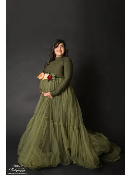This elegant studio portrait features a beautiful olive green tulle gown. The floral belt adds a delicate touch of color and detail to the simple, classic setup.