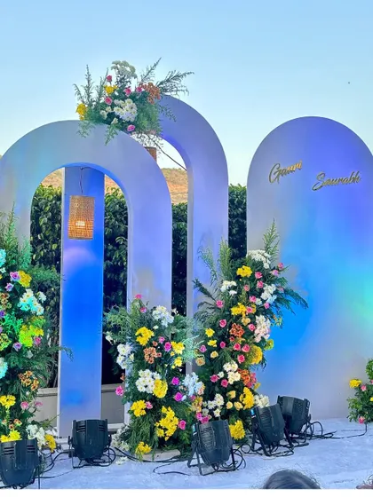 For a more modern look, I designed this wedding backdrop using custom arches and asymmetrical floral arrangements. The blue uplighting gives it a unique and stylish feel for evening events.