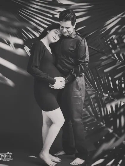 A quiet, intimate moment captured in black and white. This artistic maternity portrait uses shadows from palm leaves to create a beautiful and emotional image of the expecting couple.