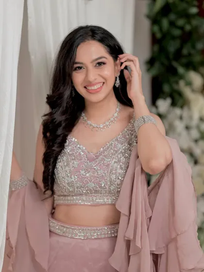 This portrait showcases the complete look, with soft waves and radiant makeup complementing her sparkling pastel lehenga.
