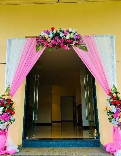 A bright and cheerful entrance with pink and white drapery and colorful floral arrangements.