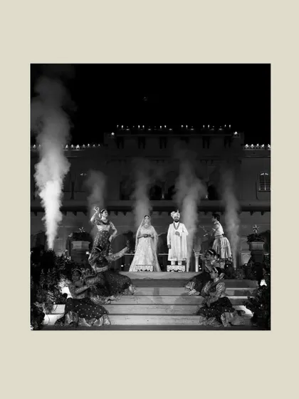 A dramatic black and white shot of Sanskriti and Rahul's grand stage presentation at Rambagh Palace, complete with theatrical smoke for a cinematic effect.