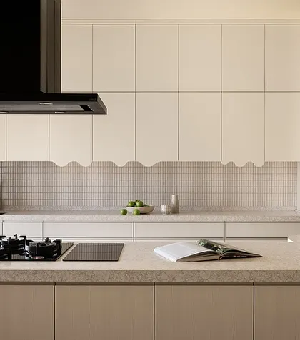 The main cooking and prep area, with a clean, minimalist design featuring white cabinets with a playful, wavy-edged detail.