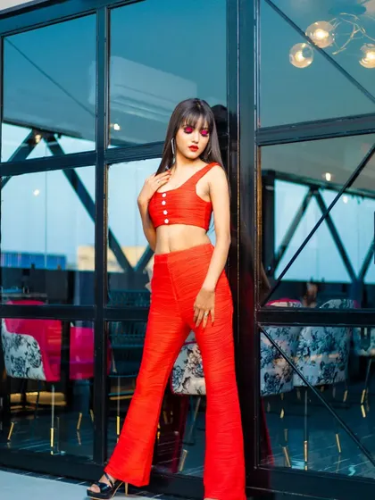 A full-length look from a modern fashion shoot. The edgy red eye makeup and matching lip pop against the all-red outfit, creating a bold, monochromatic statement.