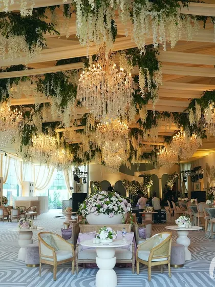The reception hall ceiling was a spectacle of hanging white wisteria and dozens of crystal chandeliers, creating a breathtaking, immersive floral sky for the evening celebration.