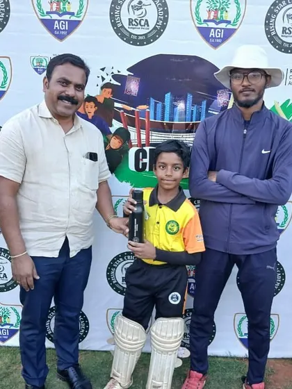 A young player proudly holds his award bottle, standing with the match official.