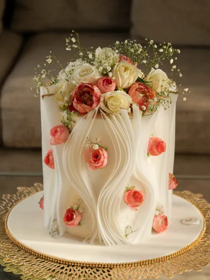 For this design, I created gentle waves with the wafer paper, embedding small pink roses within the folds. The cake is topped with a fresh bouquet of baby's breath and roses, blending edible art with natural beauty.