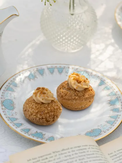 A close-up of our fluffy and creamy Choux Pastries. These light-as-air pastries are filled with a Biscoff cream and have a crunchy craquelin top, offering a delightful texture and flavour.