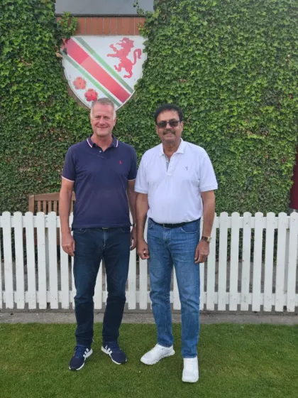 Standing with John Marshall, president of the Urmstone Cricket Club, in front of the club's ivy-covered pavilion.