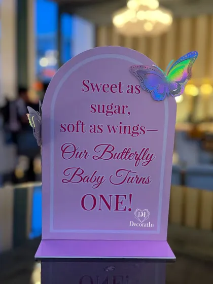 A close-up of the adorable table sign, "Sweet as sugar, soft as wings, Our Butterfly Baby Turns ONE!"