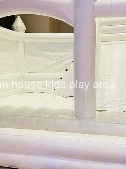 A detailed shot inside the white bounce castle, showing the climbing ramp with safety holds and the entrance to the slide.