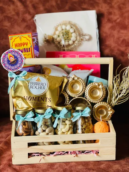 A similar wooden crate Diwali hamper, this one featuring golden diyas and a traditional Rakhi, making it suitable for Bhai Dooj as well.