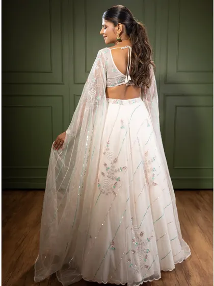 A view of the back of the white embroidered lehenga, showing the beautiful sleeve details and the delicate tie-up back. Every angle is designed to be picture-perfect.
