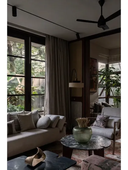 A detail shot of the living room at Pràna, focusing on the interplay of light and shadow. The large windows and sheer curtains help control the natural light, creating a soft, diffused glow throughout the day.