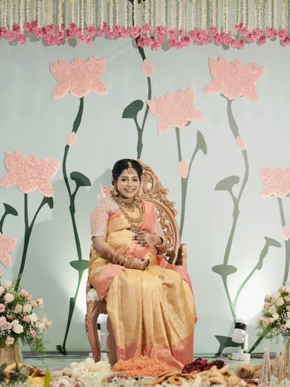 The mother-to-be glowing in her beautiful saree, seated against the custom-designed lotus backdrop.