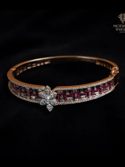A beautiful bangle that combines the fire of rubies with the brilliance of diamonds in a modern geometric pattern. The central floral diamond motif adds a touch of softness.