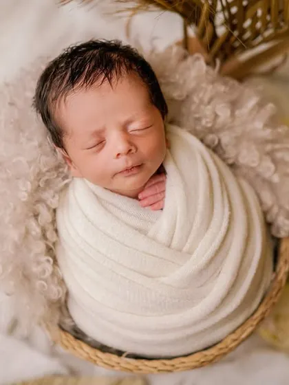 A bundle of neutral-toned softness. This classic swaddle pose is elevated by the beautiful textures of the wrap and the basket.