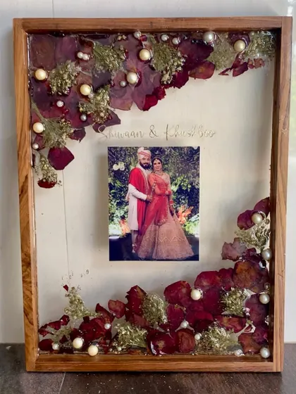 A finished varmala preservation frame in a wooden shadow box. This is a timeless way to display your wedding flowers and photo.