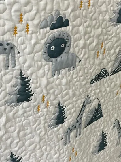 A close-up of the woodland animal baby quilt, showing the detailed embroidery and quilting.