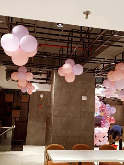 Another angle of the baby shower decor, showing how the balloon bunches are spread across the room. You can also see a glimpse of the main balloon backdrop being prepared in the corner.
