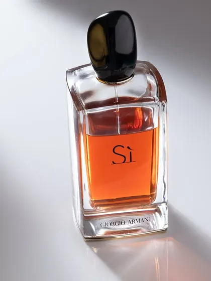 Photographing a perfume bottle requires careful control of light to highlight the glass form and the color of the liquid. The diagonal shadow adds a dynamic and artistic element to this shot.