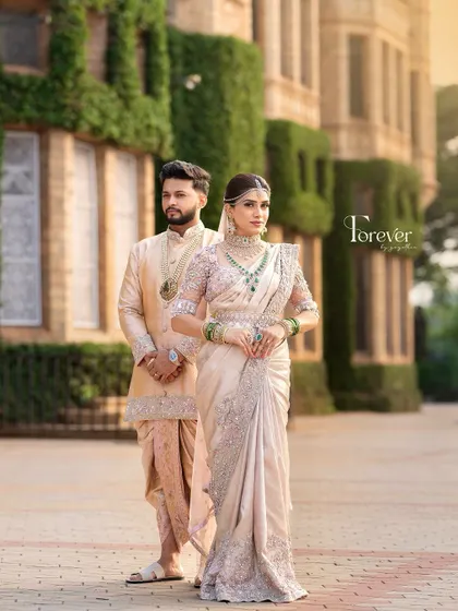 A full-length shot of the couple at the Bangalore Palace. The groom's modern sherwani and dhoti combination is a perfect example of blending contemporary style with traditional elements.