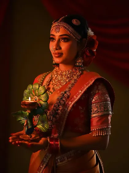 A slightly different angle, this photo shows the beautiful sheen of the silk saree and the intricate design of the peacock lamp.