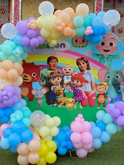 A circular Cocomelon backdrop surrounded by a rainbow of pastel balloons, featuring the entire cast of characters for a cheerful photo opportunity.