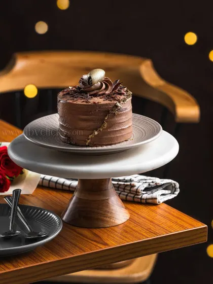 A mini chocolate cake on a tiered cake stand, creating a sense of elegance and occasion, perfect for a high-end bakery.