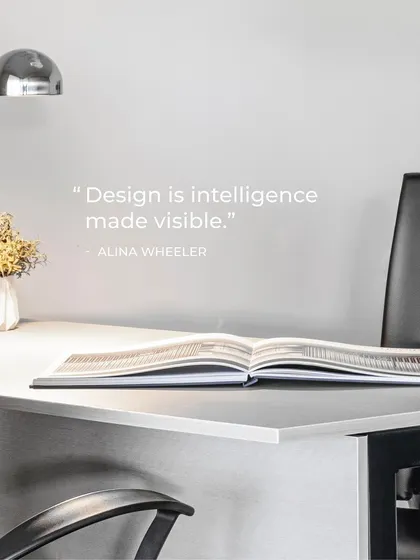 "Design is intelligence made visible." This quote by Alina Wheeler perfectly captures our philosophy. A clean desk, good lighting, and an open book represent a space ready for ideas and thoughtful work.