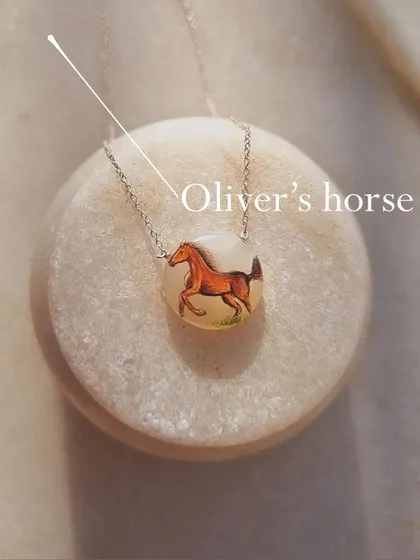 A close-up of the 'Oliver's horse' pendant, showing the delicate brushstrokes.