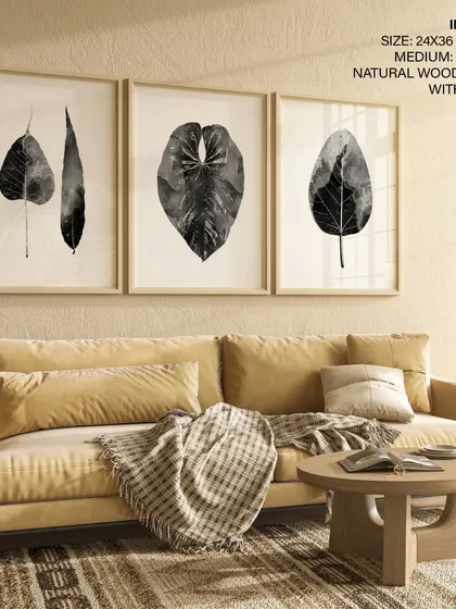 A minimalist triptych of abstract monochrome leaves. This set of three prints, framed in natural wood with glass, offers a sophisticated and modern interpretation of botanical art for a serene living space.