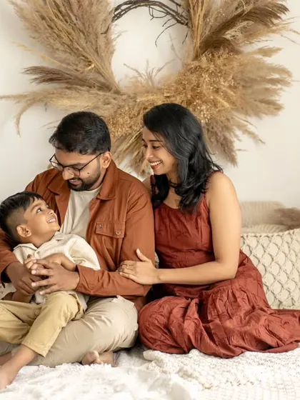 A family of three sits together on a bed in a cozy, rustic-themed studio. Their relaxed and loving interaction creates a warm and inviting family portrait.