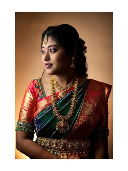 A classic portrait of a bride from her ring ceremony. The warm studio lighting enhances the rich colors of her multi-toned silk saree and heavy gold jewellery.