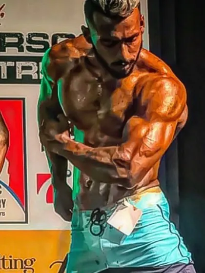 Hitting a side chest pose under the bright stage lights. The muscle striations and definition are a direct result of a perfect peak week.