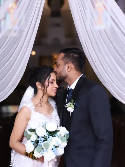 A tender kiss at the altar. The bride's elegant updo and soft makeup are perfect for this romantic, sacred moment.