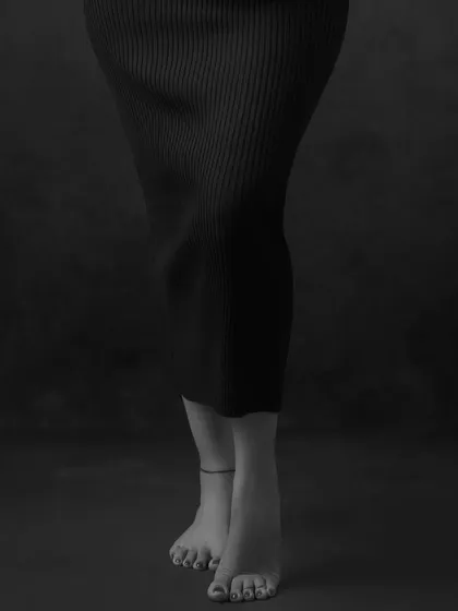 A detailed, artistic shot focusing on the mother's form and bare feet. This type of minimalist, moody photography adds a unique and elegant perspective to a maternity gallery.