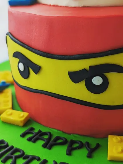 A close-up of the intense Lego ninja face on the bottom tier of this Ninjago cake. The details are all handcrafted from fondant.