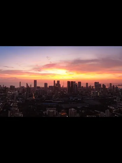 A letterboxed version of a panoramic Mumbai sunset, emphasizing the cinematic quality of the city's skyline against the colorful sky.