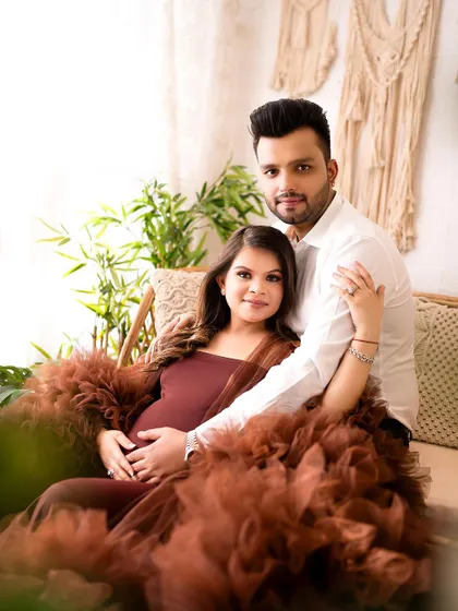 A gorgeous portrait of an expecting couple in my cozy, boho-themed studio setup. The earthy tones of the dress and decor create a warm and inviting atmosphere.