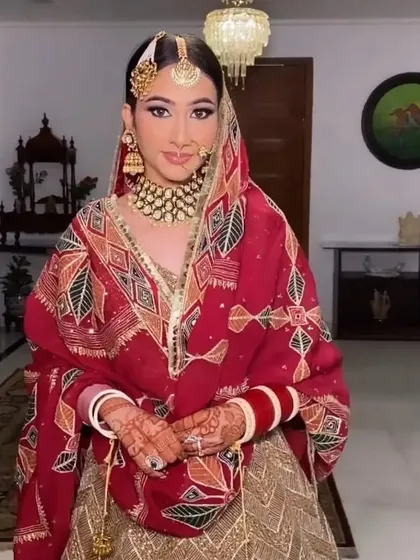 A Punjabi bride with a classic sleek bun covered by her phulkari dupatta. I ensure the bun is structured to support the dupatta and traditional hair accessories perfectly.