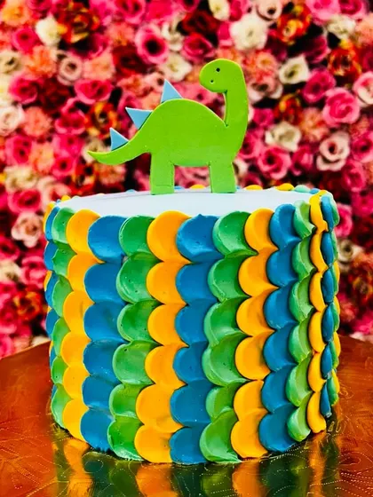 A vibrant dinosaur cake with a colorful scaly pattern and a simple topper, perfect for a modern and fun dinosaur-themed party.